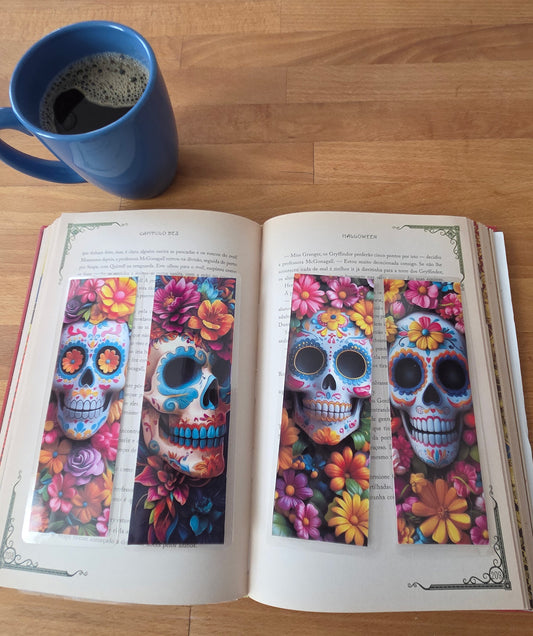 Open book with colorful skull designs on a wooden surface next to a blue mug.