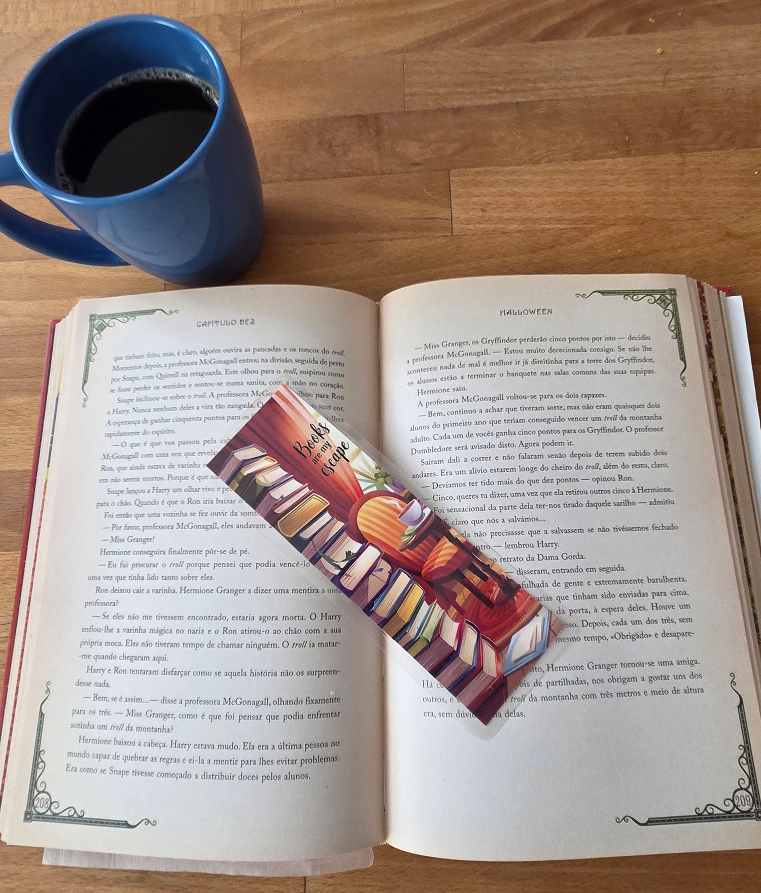 Open book with a colorful bookmark showing a stack of books and a teacup on a table